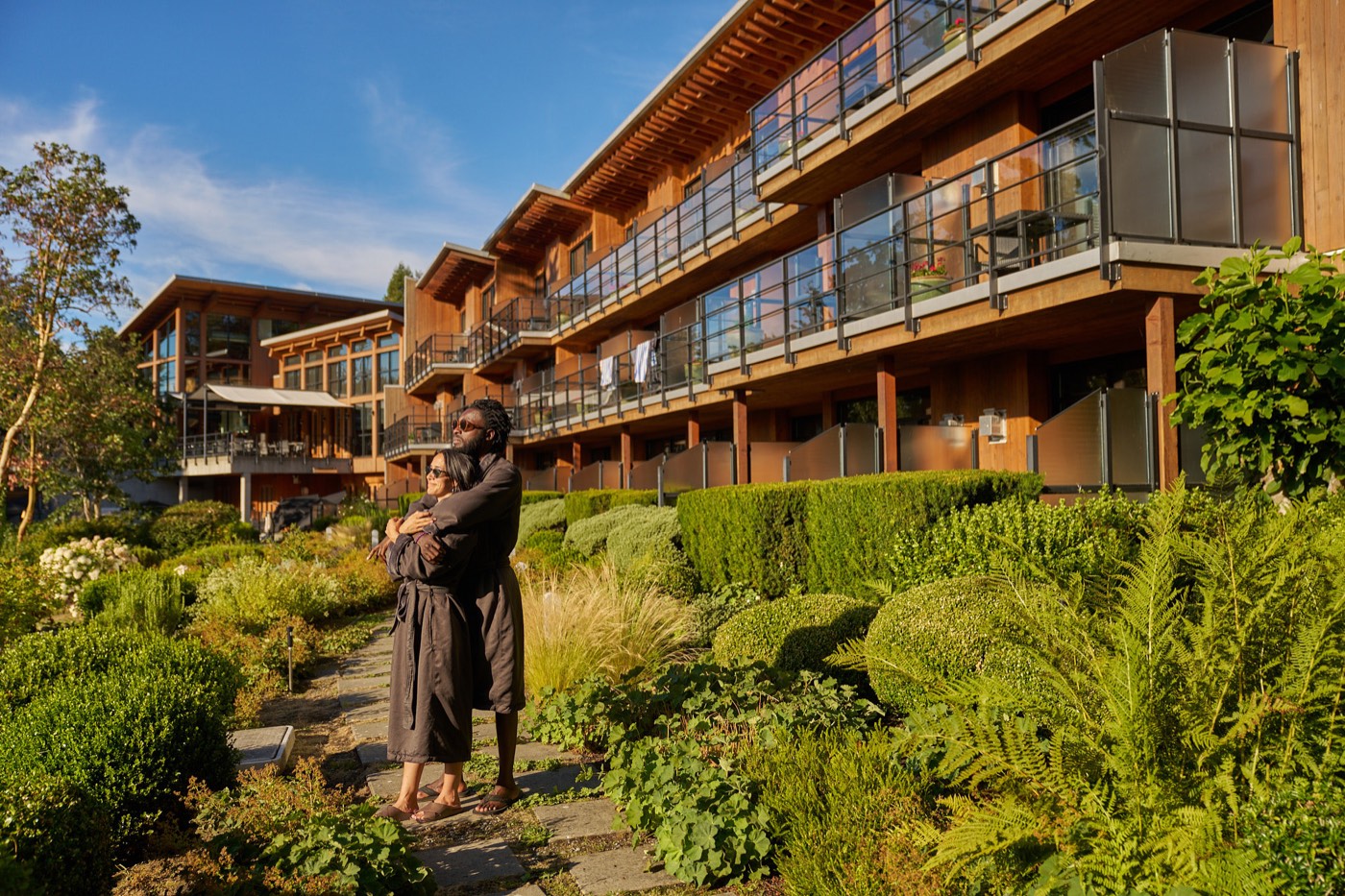 A couple in robes in the gardens beneath the resort's room balconies