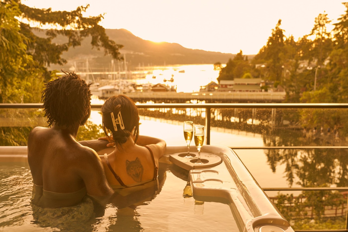 A couple with champagne in the heated pool at golden hour, overlooking the marina